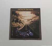 Front cover artwork of Jackson Browne Running on Empty LP showing the road with dramatic clouds and drums in foreground.