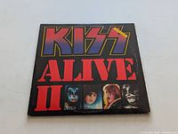 Front cover of the Kiss Alive II LP showing the title in red and purple with band member photos