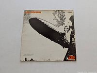 Front cover of Led Zeppelin I vinyl LP showing black and white image of Hindenburg airship explosion with Led Zeppelin text in orange and Atlantic Records logo.