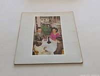 Front cover of the Led Zeppelin Presence album showing four people sitting around a table with a black obelisk object