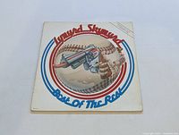 Front cover of Lynyrd Skynyrd "Best of the Rest" LP showing detailed artwork of a revolver and snake within a baseball with circular red and blue stripes and band name.