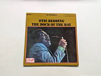 Front cover of Otis Redding LP The Dock of the Bay showing portrait of artist and album title on yellow background.