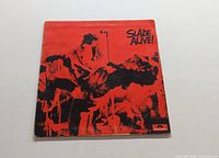 Front cover of Slade Alive album sleeve showing band members performing live in red and black design with Polydor label.
