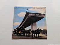 Front cover of The Doobie Brothers LP The Captain and Me showing horse-drawn carriage and unfinished highway bridge.
