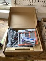 Nailer and nail packs in original cardboard box viewed from above.