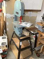 Full view of Delta band saw on stand with instruction manual on table