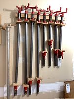Eight metal bar clamps hung on wall