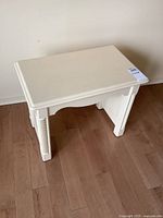 Full view of white painted wood bench showing top surface and legs.