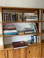 Photo showing shelves with multiple books including leather-bound volumes, craft books, and DVDs