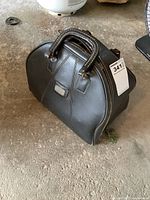 Closed black leather bowling ball carry bag sitting on floor.