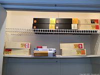 Ten Kodak Carousel 140 Transvue slide trays in their original cardboard boxes displayed on white shelves.