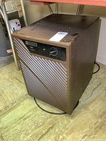 Brown Mastercraft D28 frostguard dehumidifier shown in angled side view on floor.