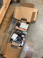 View of two cardboard boxes filled with assorted electronic parts, cables, cooling fans, and other components
