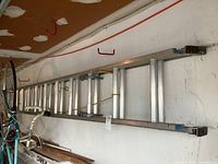 Long view of the aluminum extension ladder leaning on a wall showing the full length and condition