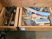Two open wooden drawers, one filled with numerous wood sanding blocks of different shapes and sizes, the other containing wooden mallets, hammers, and other tools.