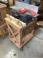 Front view of jointer/planer on wooden stand, shows cutter housing, power cord, push handles on shelf