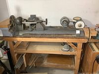 Full view of lathe mounted on wooden workbench, showing the length and attached bench grinder on one end