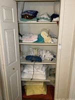 Photo of linen closet with multiple shelves filled with towels, sheets, pillows, throws, and blankets in various colors and textures.