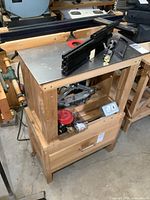 Wooden router stand front view with aluminum top plate, red insert ring and fence assembly