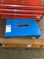 Closed blue Mastercraft case sitting on workbench with red tool chest behind