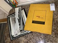 Full view of large Kodak Sheet Film folder and stack of black and white vintage photos on countertop