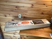 Full view of boxed vintage Sterling model plane kit sitting on wooden furniture.