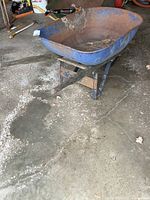 Front view showing blue metal tray with rust and wood handles extending outward.