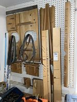 Wall-mounted wooden jigs and attachments in a workshop setting showing several sizes and shapes, some with metal strap supports.