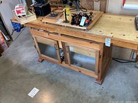 Overall view of wood workbench showing top, vises, and storage base