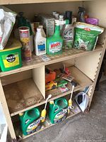 Shelving unit holding various garden chemicals and products including herbicides, plant food, fungicides, gloves, and garbage bags.