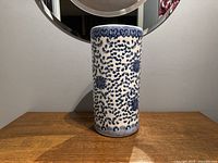 Front view of the blue and white ceramic umbrella stand showing hand painted floral and vine design.