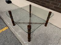 Square glass top coffee table with faux bamboo wood frame and crossbar base.