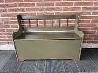 Front view of vintage painted farmhouse storage bench closed lid against brick wall background