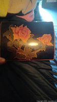 Top view of a black lacquer box with hand-painted orange-pink roses and green leaves.