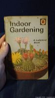Front cover of 'Indoor Gardening' book showing a planter with assorted cacti and flowers.
