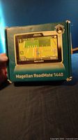 Teal and yellow product box with Magellan RoadMate 1440 branding and image of the GPS device on front.