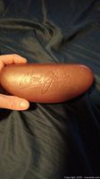 Closed brown hard case with embossed Maui Jim logo, held in hand.