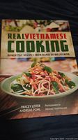 Photo of the cookbook titled 'Real Vietnamese Cooking' featuring a Vietnamese dish on the cover with herbs and noodles.