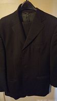 Full view of the pinstripe Italian suit jacket hanging on a hanger showing the front and lapel details