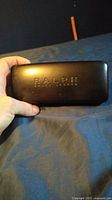 Black protective Ralph Lauren sunglass case with embossed logo held in hand