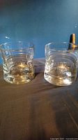 Photo of two clear Gibson whiskey glasses side by side on a dark surface with embossed Gibson branding visible.