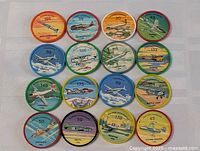 Top down view of 16 vintage Jell-O plane coins arranged in a 4x4 grid showing distinct aircraft and colorful background skies in different colors and numbers.