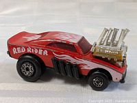 Side view of the red Matchbox Red Rider die cast toy car showing flame decals and engine detail.