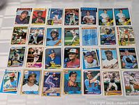 Top view photo showing 28 Topps baseball cards laid out in rows, visible player images and team logos.