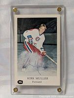 Front of the hockey card showing Kirk Muller skating in Canadiens uniform with autograph signature, encased in clear acrylic holder with brass screws.
