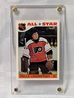 Front view of the 1985-86 OPC All Star Pelle Lindbergh hockey card inside a clear screw-down holder, showing player in Flyers uniform with goalie gear.