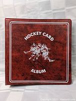 Brown hockey card album with embossed 'Hockey Card Album' text and three hockey players on the front cover.