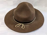 Front view of brown antique Boy Scouts hat showing felt material, leather band, and cord detail.