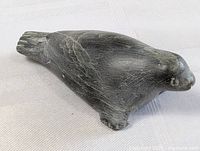 Front profile view of the carved soapstone seal showing smooth texture, carved feet and detailed head.