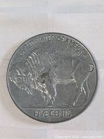 Front view of large metal novelty display resembling a Buffalo nickel coin, showing the buffalo profile and inscriptions.